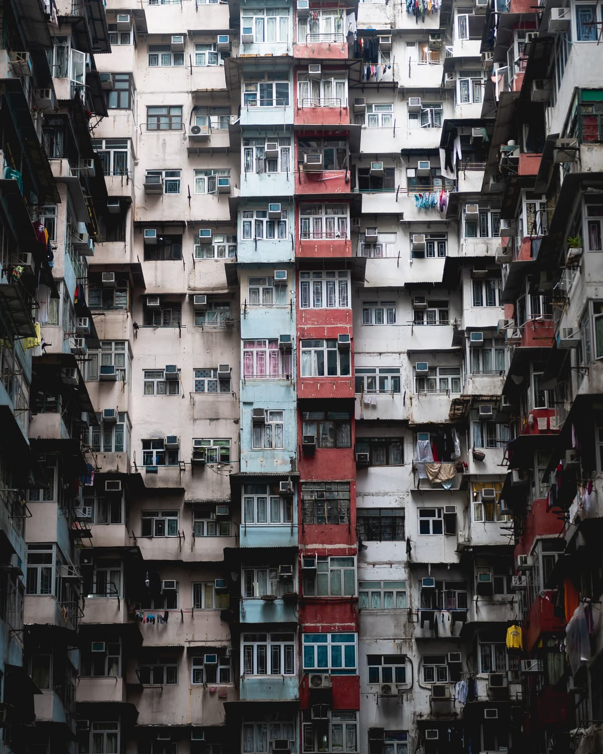 Dense facade of a towering residential building in Quarry Bay, Hong Kong, covered in colorful windows and air conditioning units
